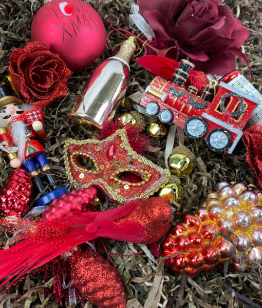 Rød julepynte pakke i julens farver med detaljer i guld. julepynt fra kugler til tog til mere anderledes julepynt såsom flasker til masker.